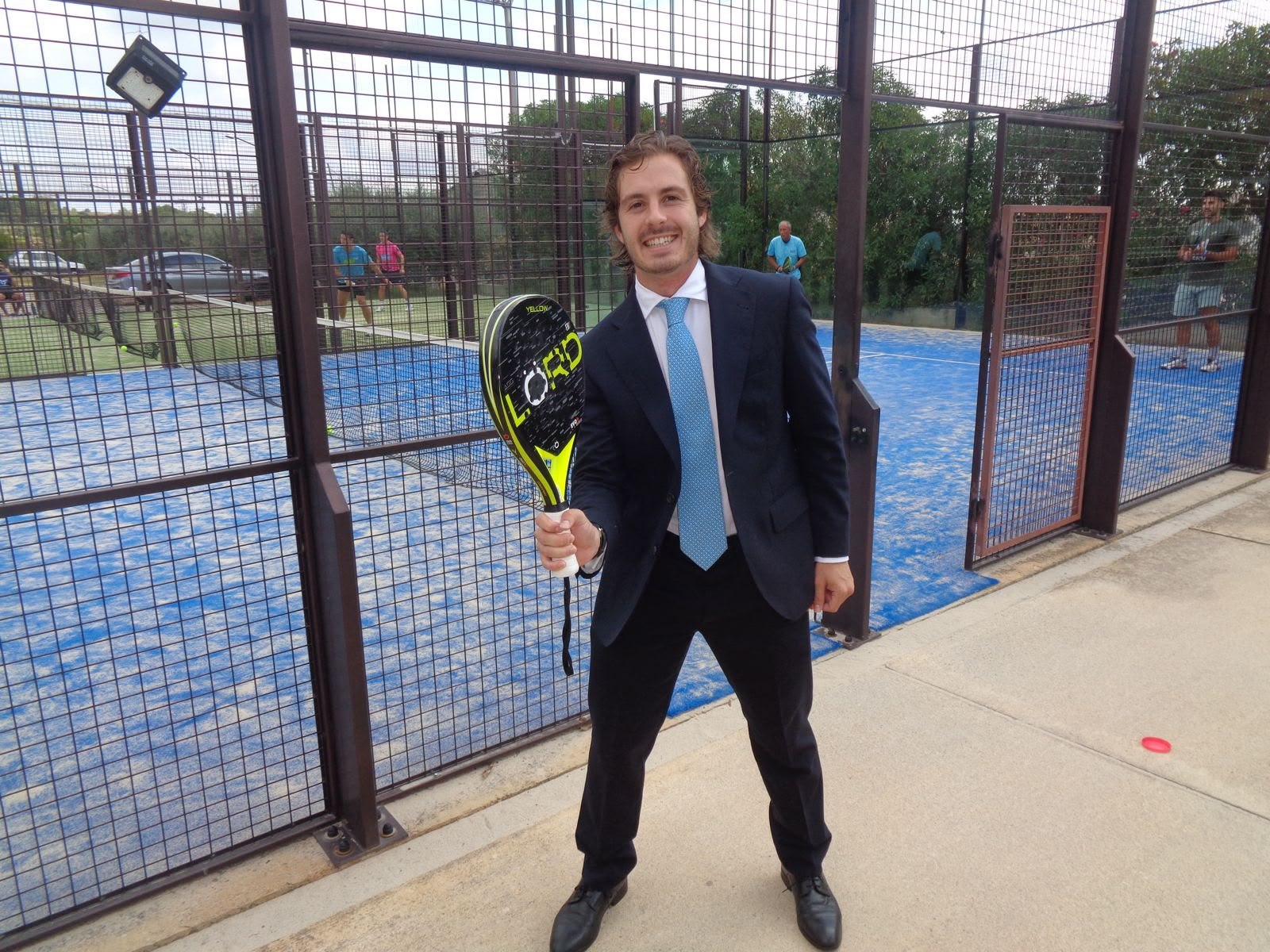 Un amigo con traje junto a las pistas de pádel